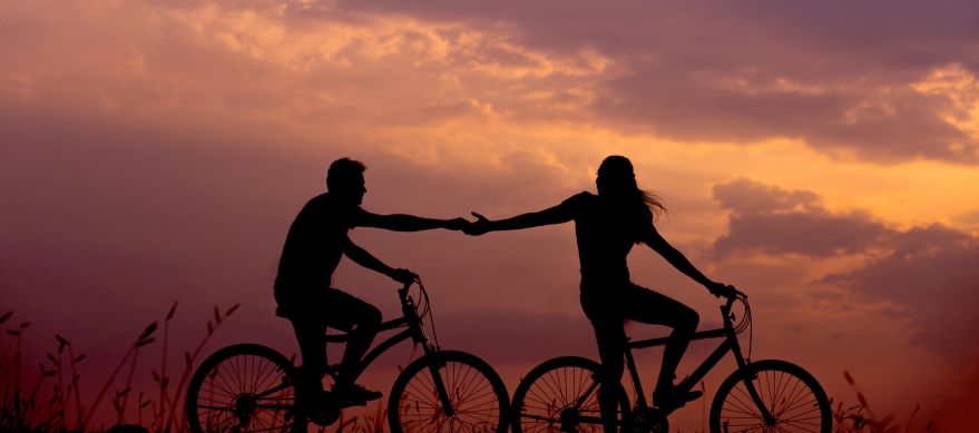 Kærestepar holder hånd i mens de cykler