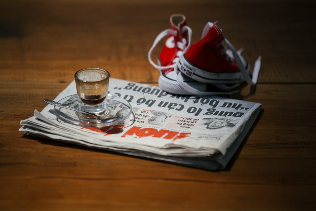 Sko, avis, og et glas på et bord